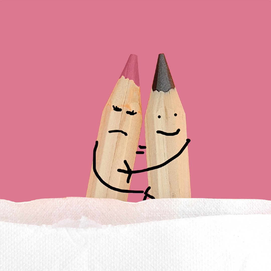 pink background showing the tips of 2 sharp pencils close beside each other. there are faces and arms drawn on each pencil to look like they are in an embrace. one is not happy. 