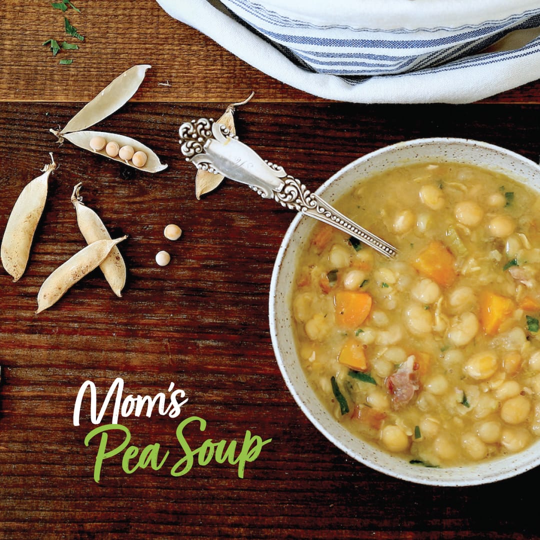 looking down on a dark wooden board with a hearty bowl of yellow pea soup on it