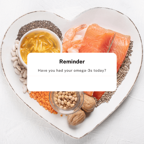 Heart shaped plate with raw fish, raw prawns, chai seeds, shelled walnuts, and lentils. on top of the image is a text box. It reads "Reminder Have you had your Omega 3s today?" 