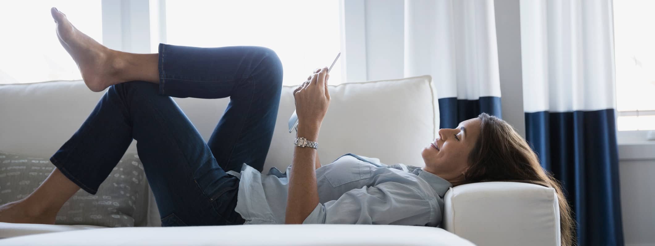 Woman relaxing on a couch with a digital tablet.