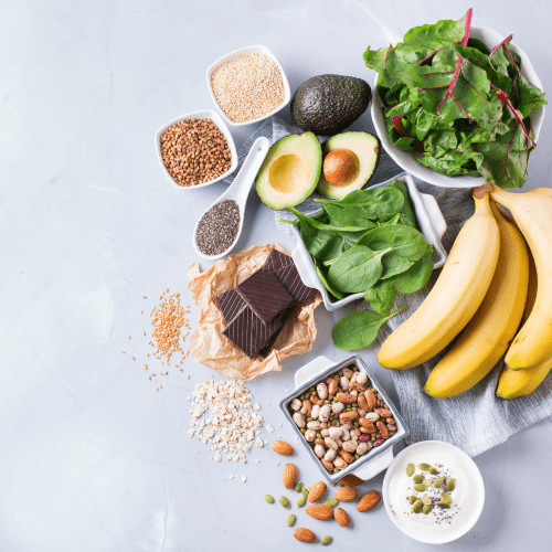 A collection of magnesium rich foods - bananas, dark chocolate, spinach, kale, avocado, nuts and seeds, chai