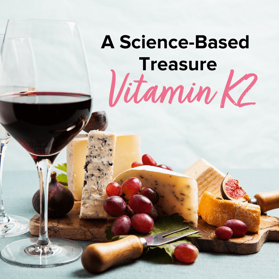 Text that reads "A Science-Based Treasure Vitamin K2" placed above a cheese board with 4 different kinds of cheese, grapes, and figs. There is a glass of red wine and a glass of white wine standing beside the cheeses. 